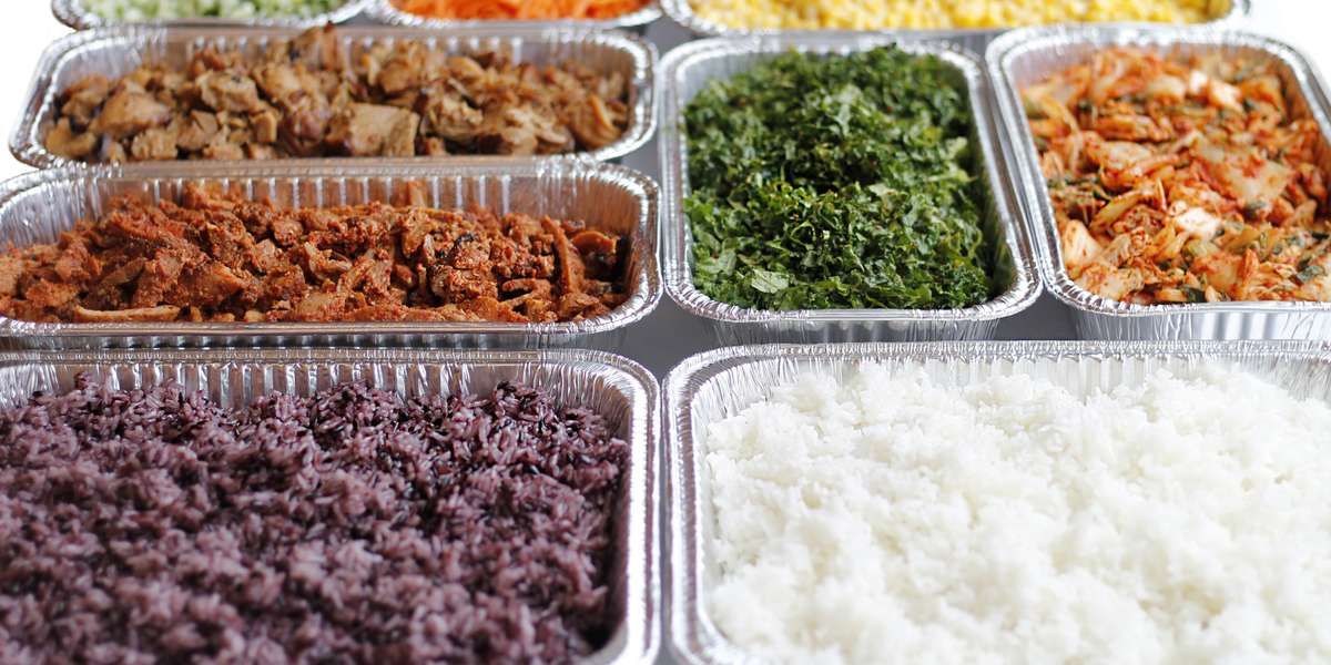 A catered spread from Seoul Spice that includes rice, vegetables, and meat.