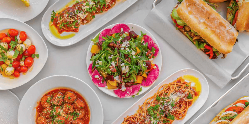 A catered Italian spread of sandwiches, pasta, and salad.